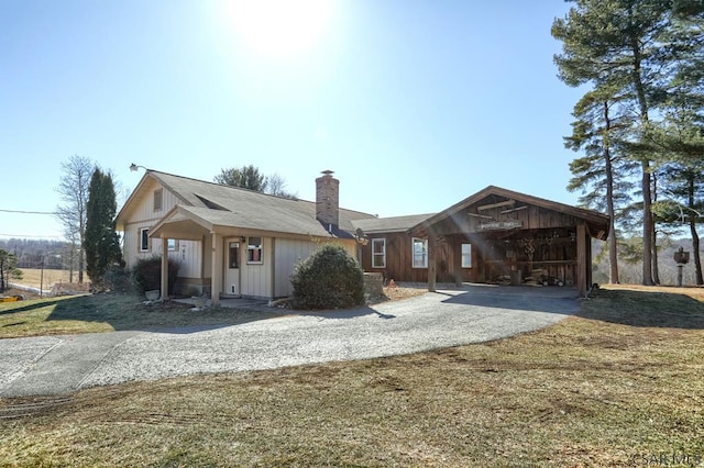 view of front of home featuring a front yard, driveway, and a chimney