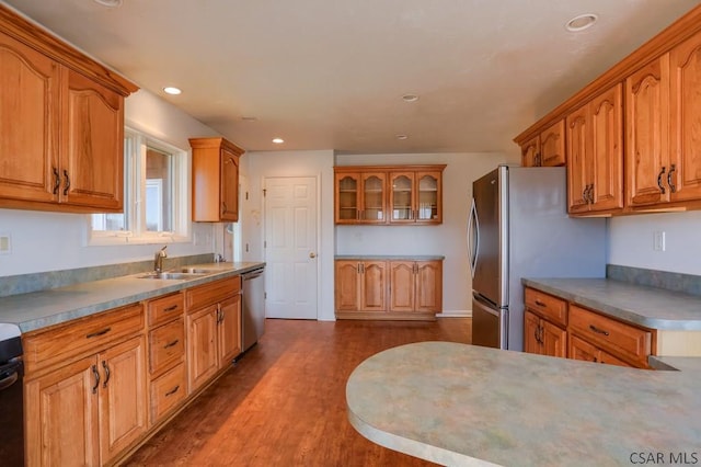 kitchen featuring brown cabinetry, dark wood finished floors, stainless steel appliances, and a sink