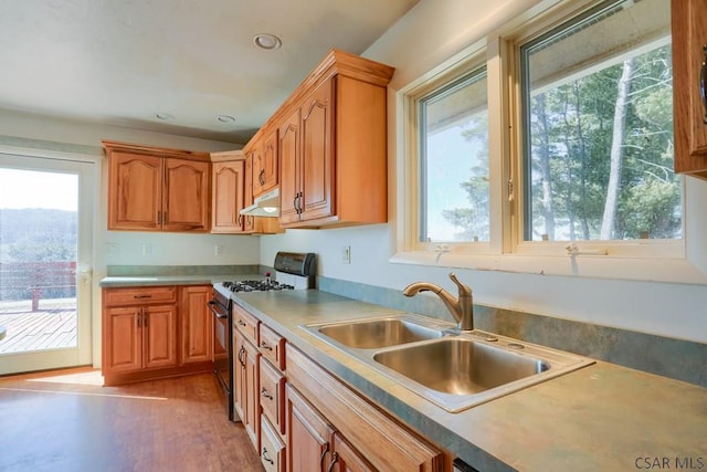 kitchen featuring a sink, gas range, under cabinet range hood, and a wealth of natural light