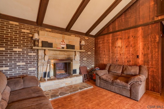 living room with a fireplace, lofted ceiling with beams, wood finished floors, and brick wall