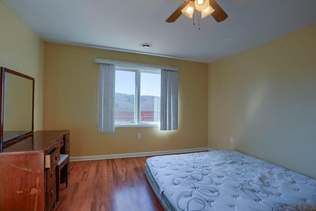 bedroom with ceiling fan, wood finished floors, visible vents, and baseboards