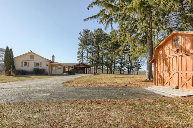 view of yard featuring a storage shed, an outbuilding, and aphalt driveway