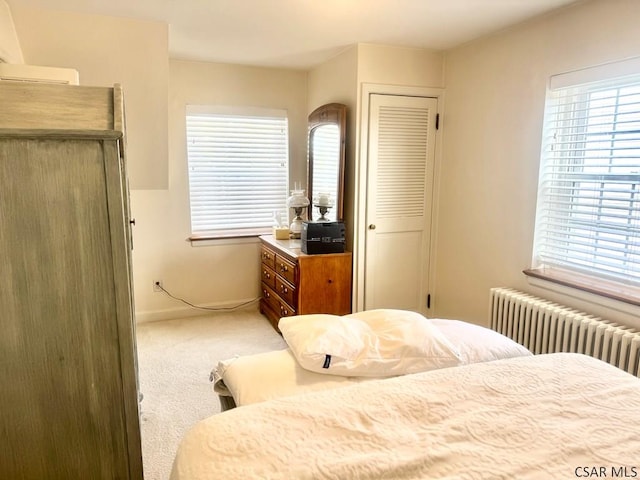 bedroom featuring radiator heating unit, carpet, and multiple windows