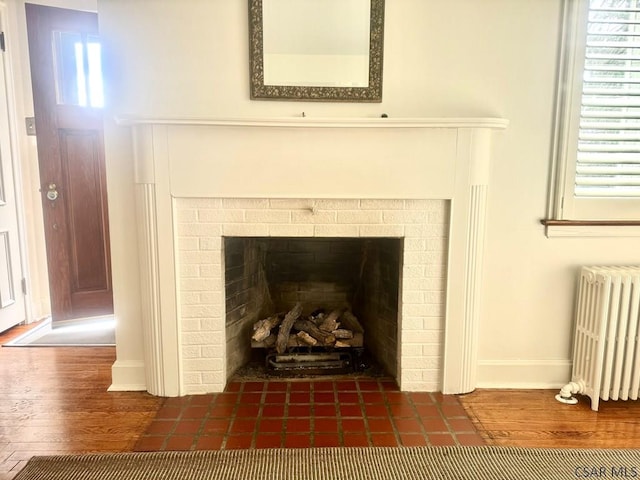 details featuring radiator, hardwood / wood-style floors, and a tile fireplace