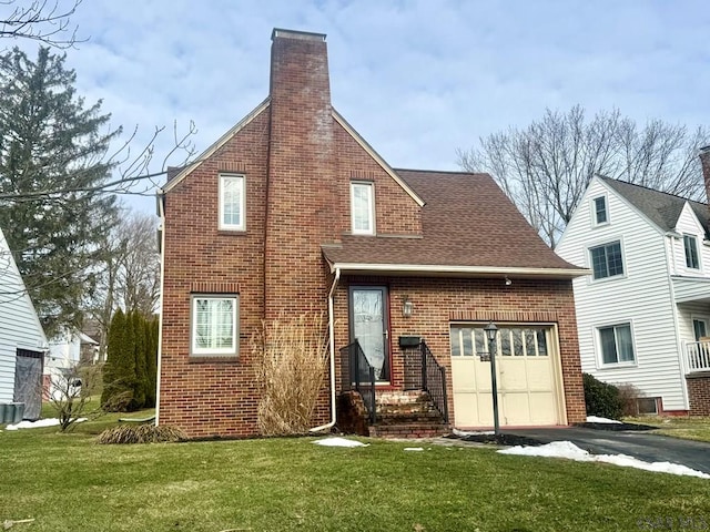 rear view of house featuring a garage and a lawn