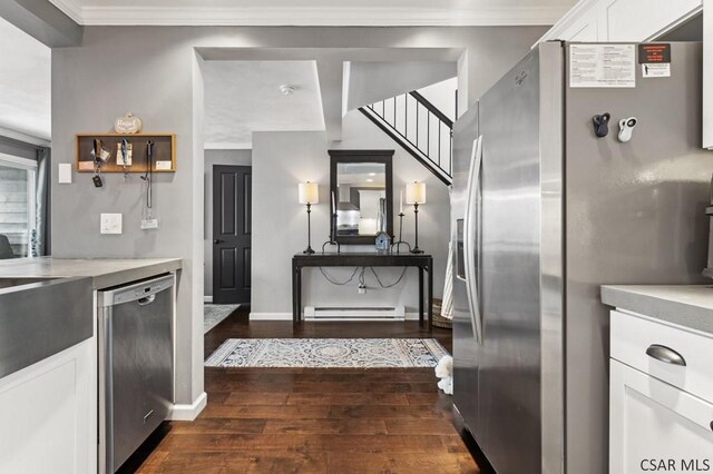 kitchen with white cabinets, ornamental molding, dark wood-type flooring, stainless steel appliances, and light countertops