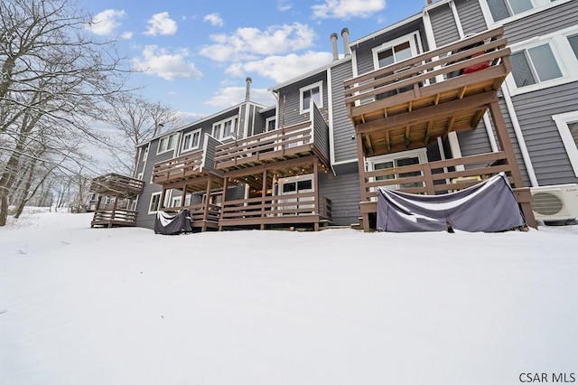 snow covered back of property featuring ac unit and a deck