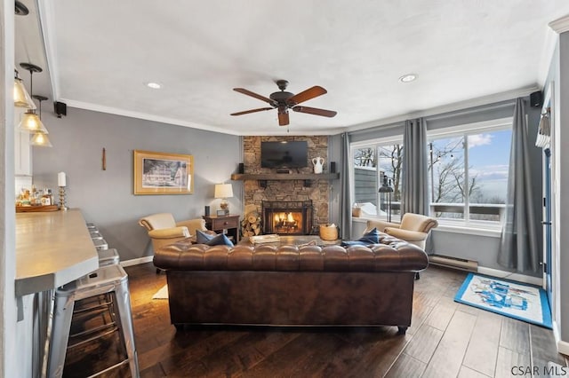 living room featuring a fireplace, baseboard heating, ornamental molding, ceiling fan, and wood finished floors