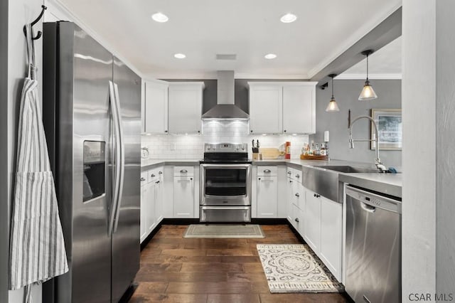 kitchen featuring dark wood finished floors, wall chimney exhaust hood, a sink, stainless steel appliances, and backsplash