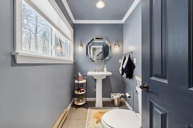 half bathroom featuring crown molding, toilet, a sink, baseboards, and tile patterned floors