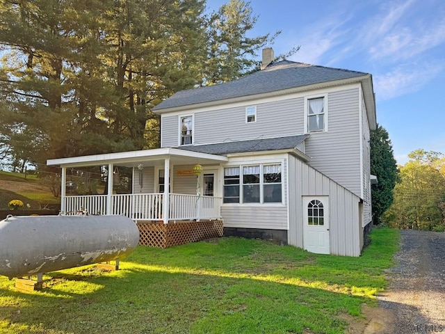 rear view of house with covered porch and a lawn