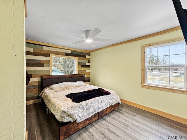 bedroom with ornamental molding, wood finished floors, a ceiling fan, and baseboards