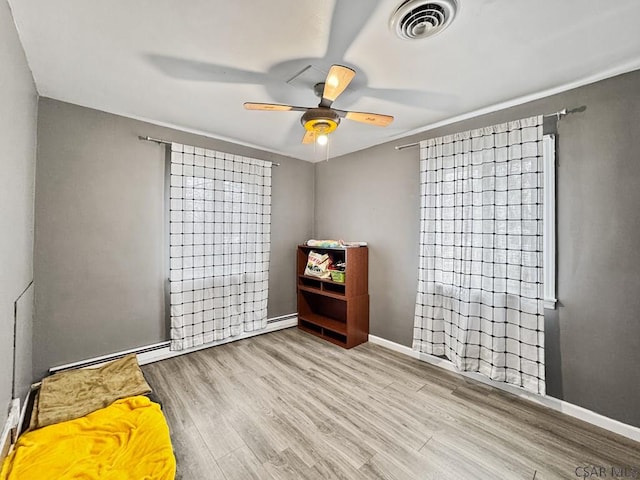 interior space with visible vents, a ceiling fan, light wood-style flooring, and baseboards