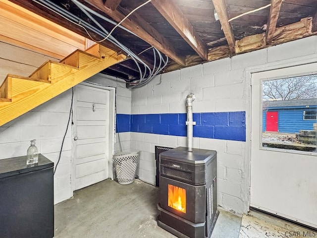 below grade area featuring concrete block wall and a wood stove