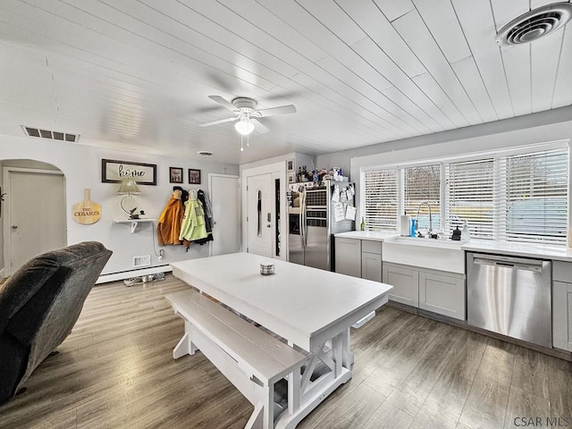 kitchen with arched walkways, stainless steel appliances, light countertops, visible vents, and gray cabinetry