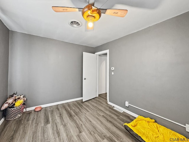 interior space with a ceiling fan, visible vents, baseboards, and wood finished floors