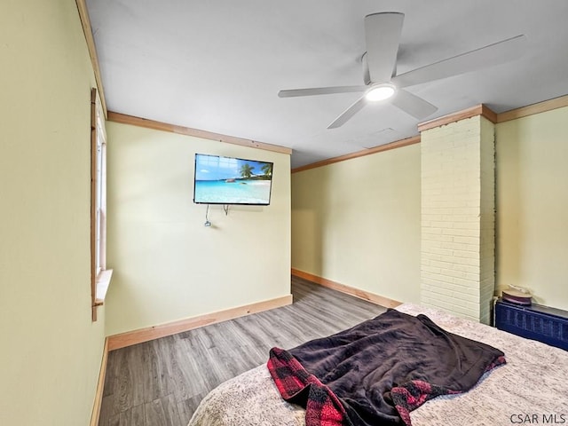 bedroom with baseboards, light wood-type flooring, a ceiling fan, and crown molding