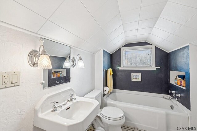 bathroom featuring sink, a bathtub, vaulted ceiling, and toilet