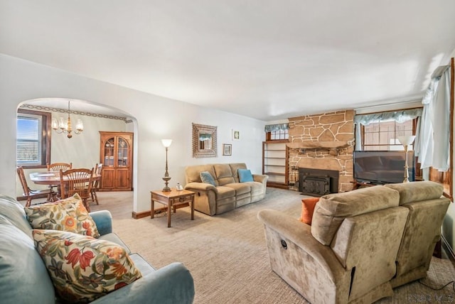 carpeted living room featuring a notable chandelier and a fireplace