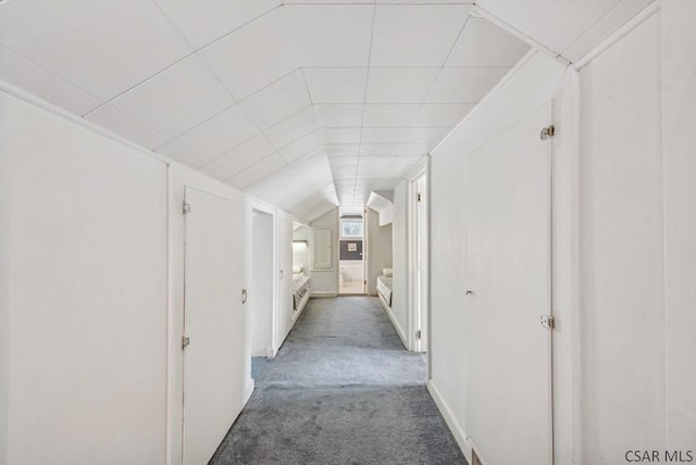 hallway featuring lofted ceiling and dark carpet