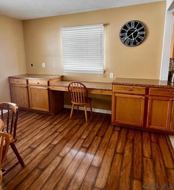 unfurnished office featuring dark wood-type flooring and built in desk