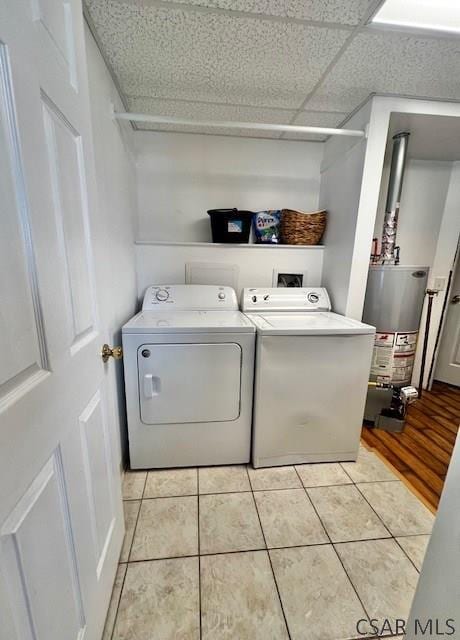 laundry area with light tile patterned flooring, washing machine and clothes dryer, and gas water heater