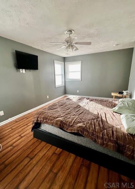 bedroom with hardwood / wood-style flooring, a textured ceiling, and ceiling fan