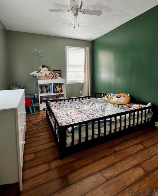 bedroom with dark wood-type flooring, a textured ceiling, and ceiling fan