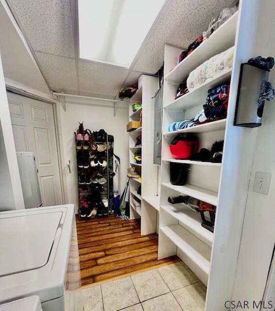 walk in closet with a drop ceiling, washer / dryer, and light tile patterned flooring