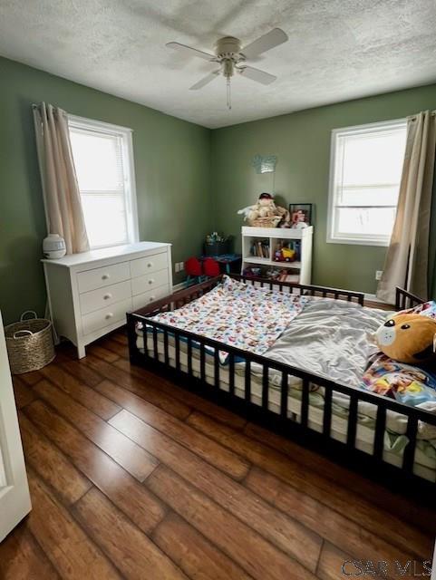 bedroom featuring dark hardwood / wood-style flooring, a textured ceiling, and ceiling fan