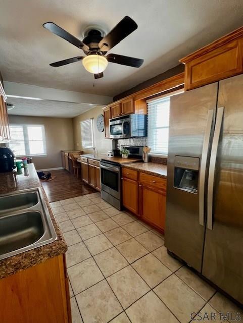 kitchen with appliances with stainless steel finishes, sink, light tile patterned floors, and ceiling fan