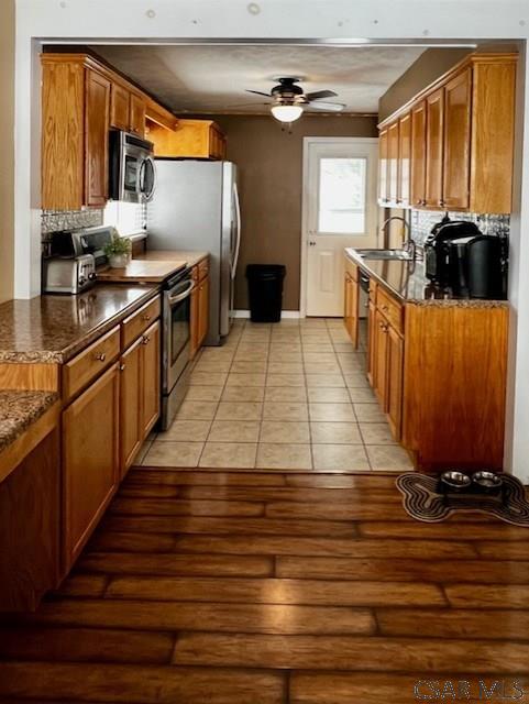 kitchen with light tile patterned flooring, sink, ceiling fan, stainless steel appliances, and backsplash