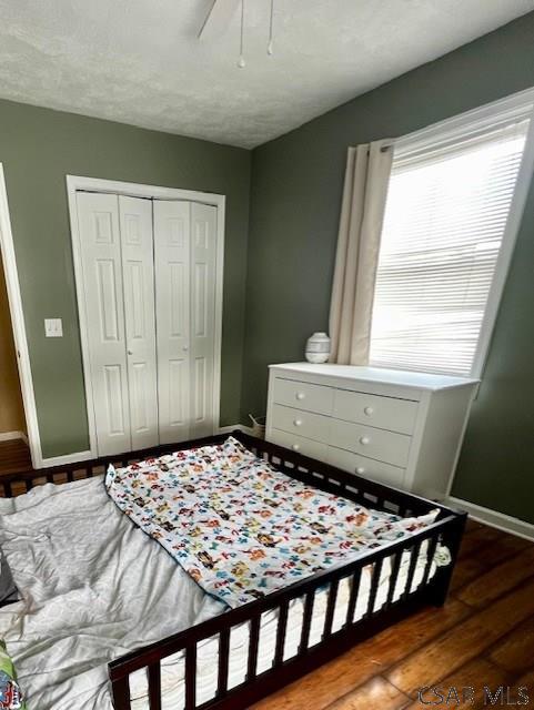 bedroom featuring dark hardwood / wood-style floors, ceiling fan, and a closet