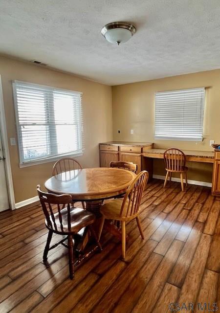 dining area with dark hardwood / wood-style flooring and a textured ceiling