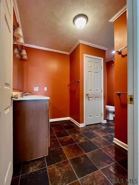 interior space with ornamental molding, vanity, a textured ceiling, and toilet