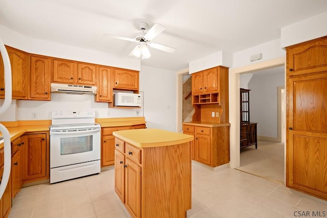 kitchen featuring white appliances, range hood, a center island, light countertops, and ceiling fan