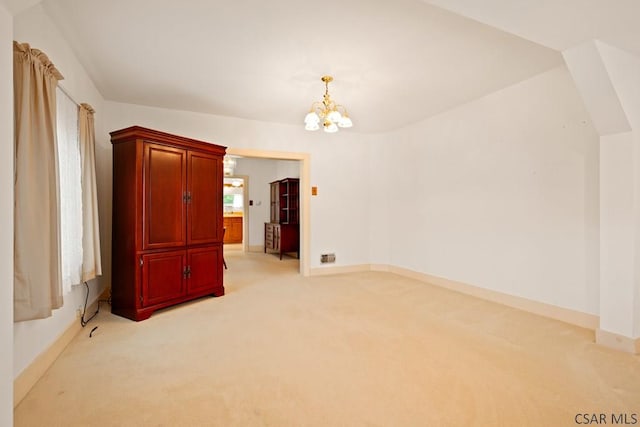 spare room with a chandelier, light carpet, and baseboards