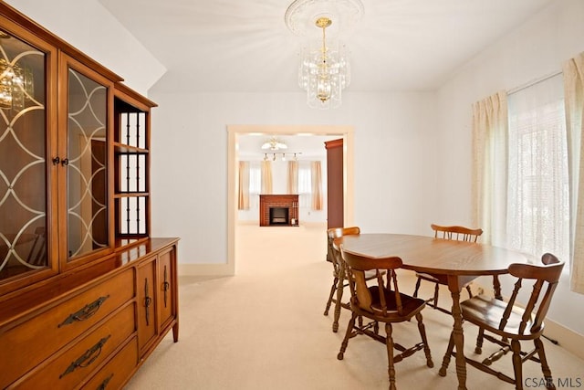 dining space with a chandelier, light carpet, and a brick fireplace
