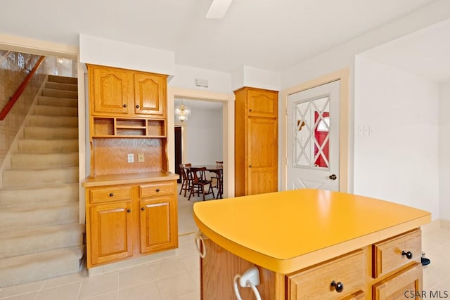 kitchen with light countertops, light tile patterned flooring, open shelves, a center island, and brown cabinetry