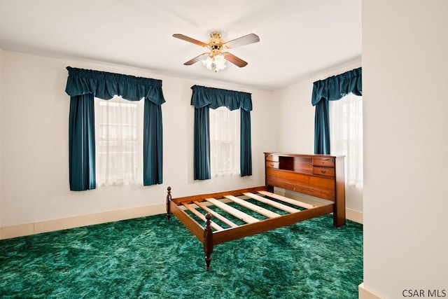 carpeted bedroom featuring multiple windows, baseboards, and ceiling fan