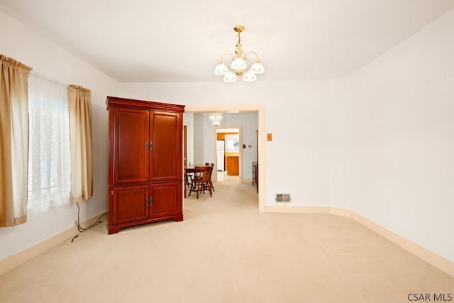 spare room with a chandelier and light colored carpet