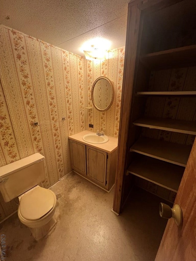 bathroom with vanity, toilet, and a textured ceiling