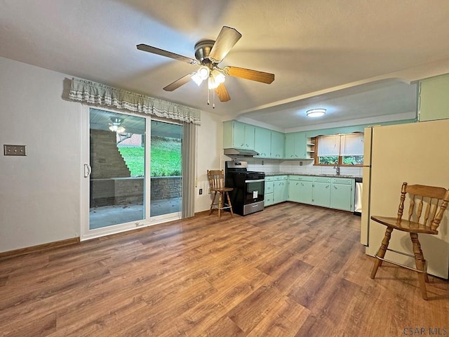 kitchen with sink, gas stove, white fridge, ceiling fan, and hardwood / wood-style floors