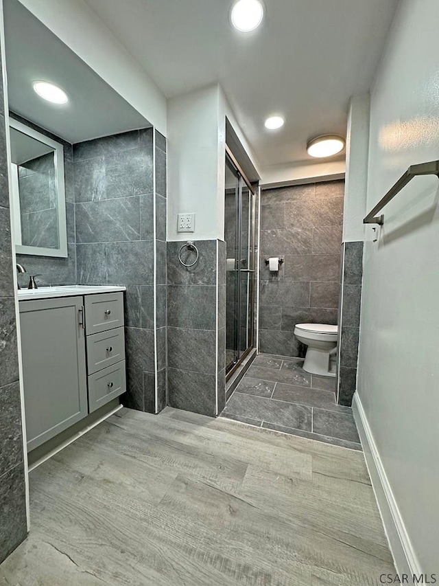 bathroom with vanity, toilet, tile walls, and walk in shower