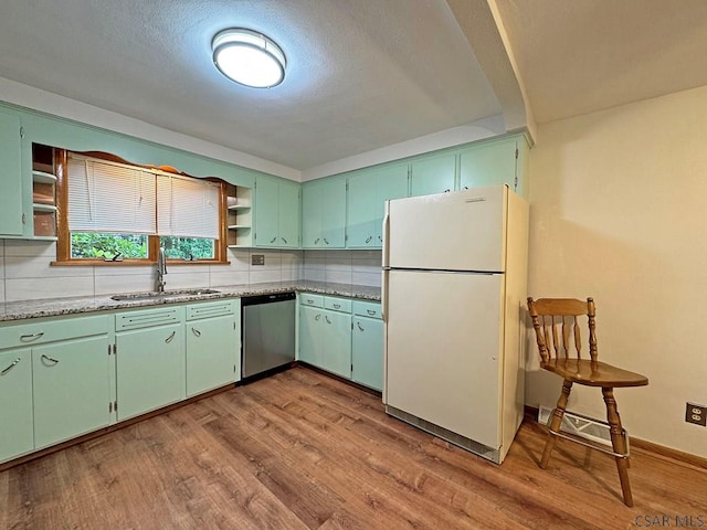 kitchen featuring sink, stainless steel dishwasher, white fridge, light hardwood / wood-style floors, and decorative backsplash