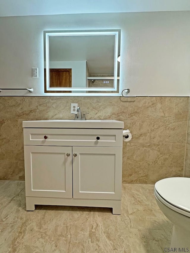 bathroom with vanity, toilet, and tile walls