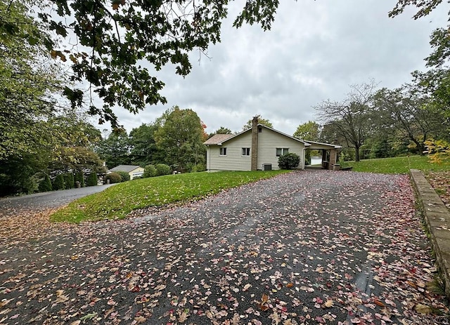 view of property exterior featuring a carport and a lawn