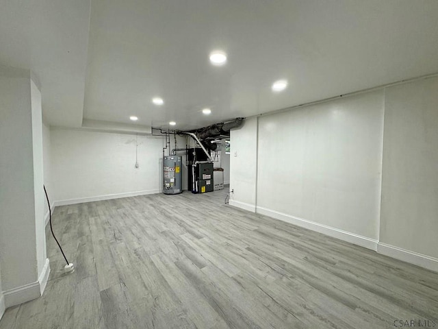 basement with heating unit, light hardwood / wood-style floors, and water heater