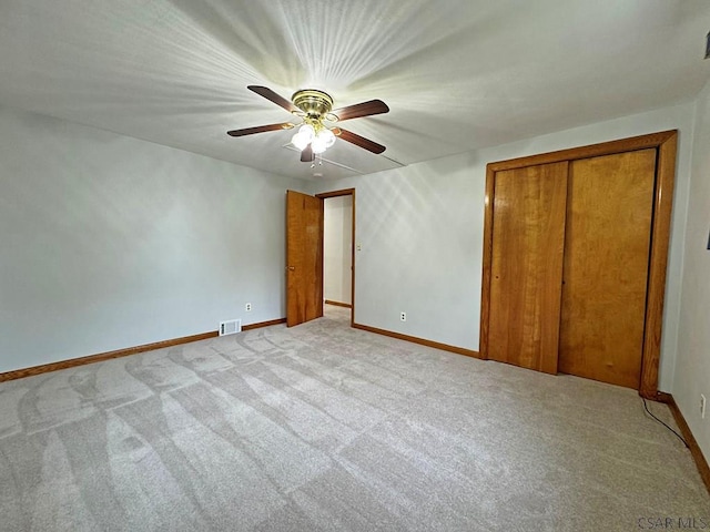 unfurnished bedroom featuring ceiling fan, light colored carpet, and a closet