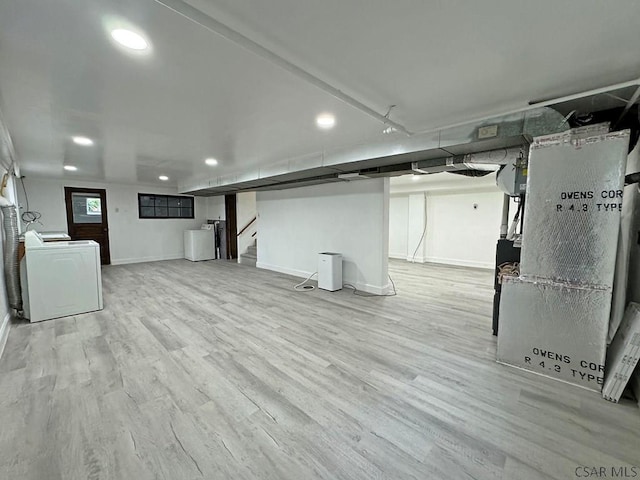 basement with washer / clothes dryer, heating unit, and light hardwood / wood-style floors